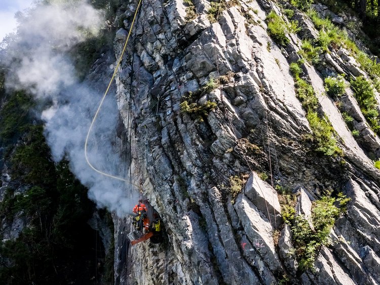 Foto: Aufnahme von unten, Fels-Kletterer im Einsatz auf einer steilen Felswand