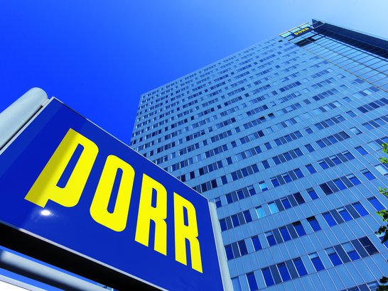 View from below of the PORR high-rise building with the PORR sign in front of it