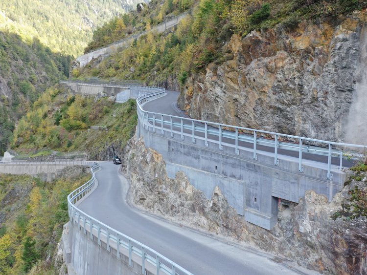 Foto: kurviger Teilabschnitt der Bristenstrasse mit Stützmauern in bewaldeter Berglandschaft 
